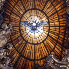 A white dove with outspread wings glows at the center of an amber window, ringed by golden rays, sculpted clouds and angels.