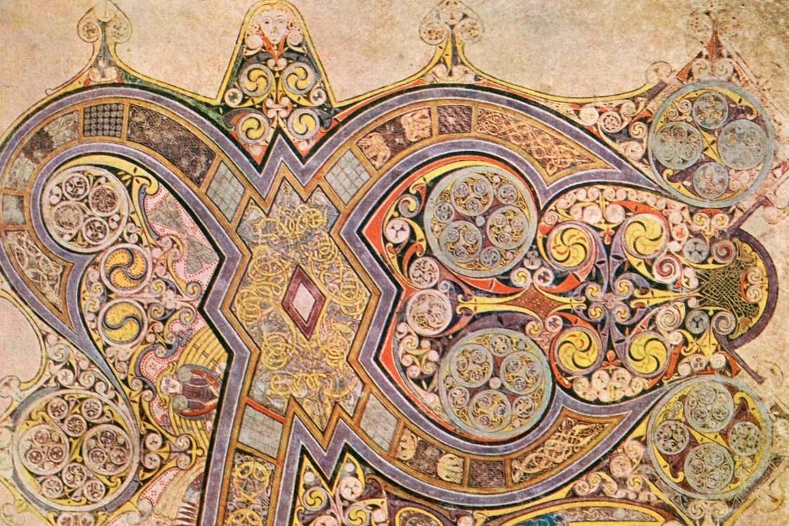 A full manuscript page filled by the giant interlaced Greek letters Chi and Rho, crowded with spirals, knotwork, tiny angels, and animals in gold, purple, and red.