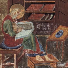 A haloed scribe sits on a stool writing in a book on his lap, in front of an open cupboard stacked with bound volumes.