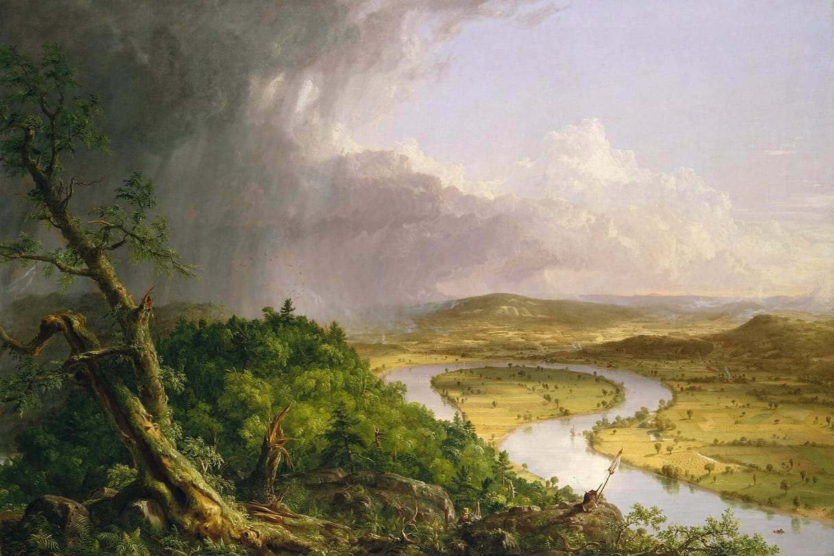 From a wooded, storm-battered hilltop, a river curves in a wide loop through sunlit farmland, while a dark thunderstorm moves off across the sky at the left.