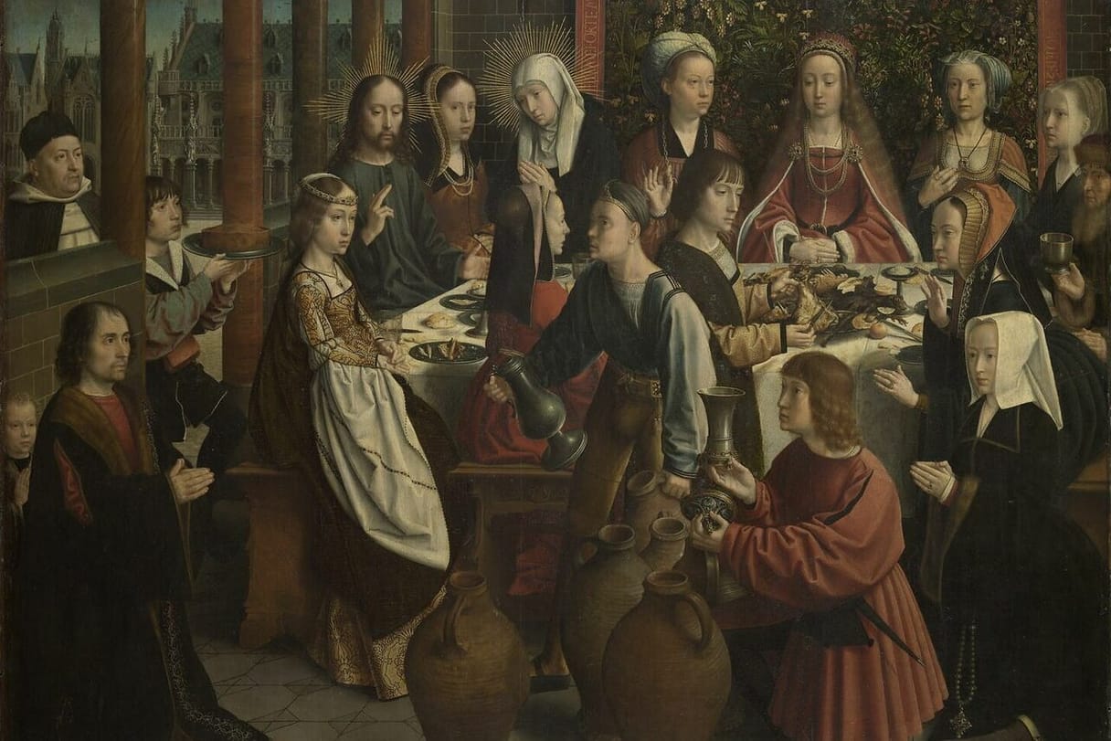 Jesus, with a golden halo, raises his hand in blessing at a crowded wedding table beside his mother, while servants pour from pitchers and large clay jars stand on the floor.
