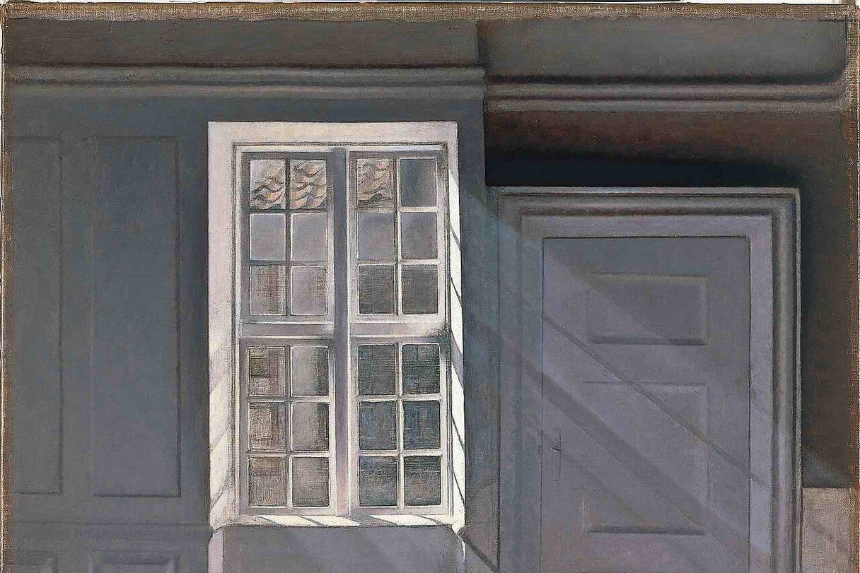 Sunlight slants through a tall window into a quiet, empty gray room, falling in bright patches on the bare floor.