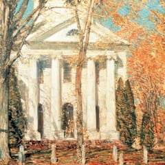A white New England church with a columned portico stands among autumn trees with orange leaves under a blue sky.