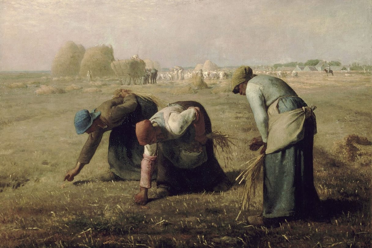 Three peasant women bend low in a harvested field to pick up stray stalks of grain, while haystacks and a busy harvest crew fill the distance.