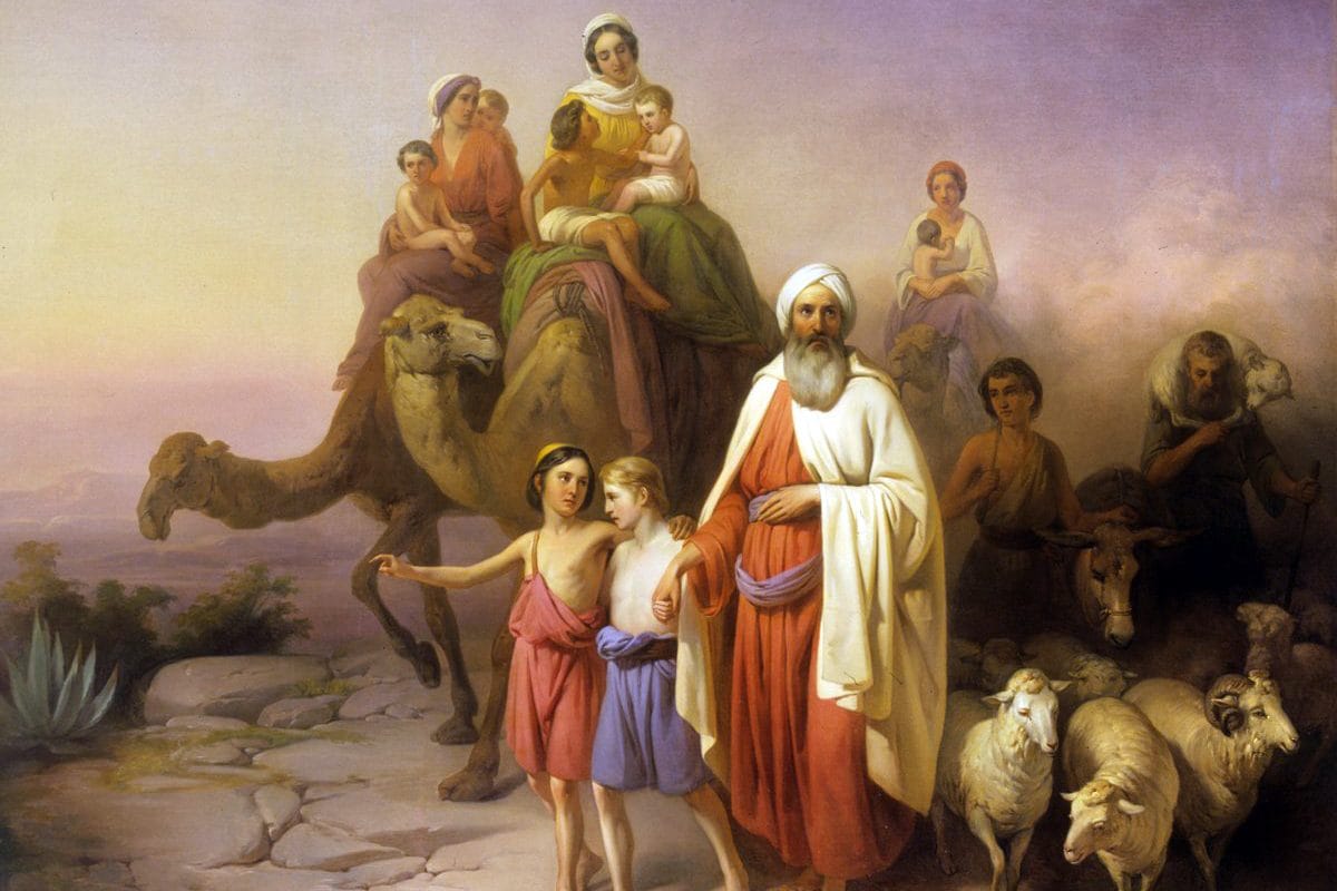 An old bearded man in a white turban and red robe walks ahead of two boys, camels carrying women and children, and a flock of sheep across a rocky plain at dawn.