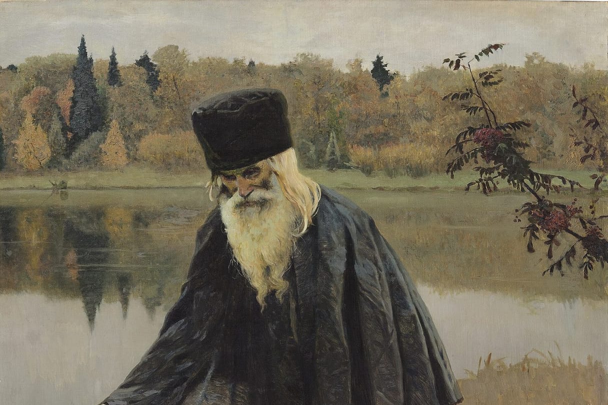 An old monk with a long white beard and a tall black cap leans on a wooden staff beside a still autumn lake, wrapped in a dark cloak, with golden trees and dark firs reflected in the water behind him and a branch of red rowan berries at the right.