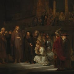 In a vast, dark temple, a woman in white kneels in a pool of light before Jesus as her accusers crowd around.