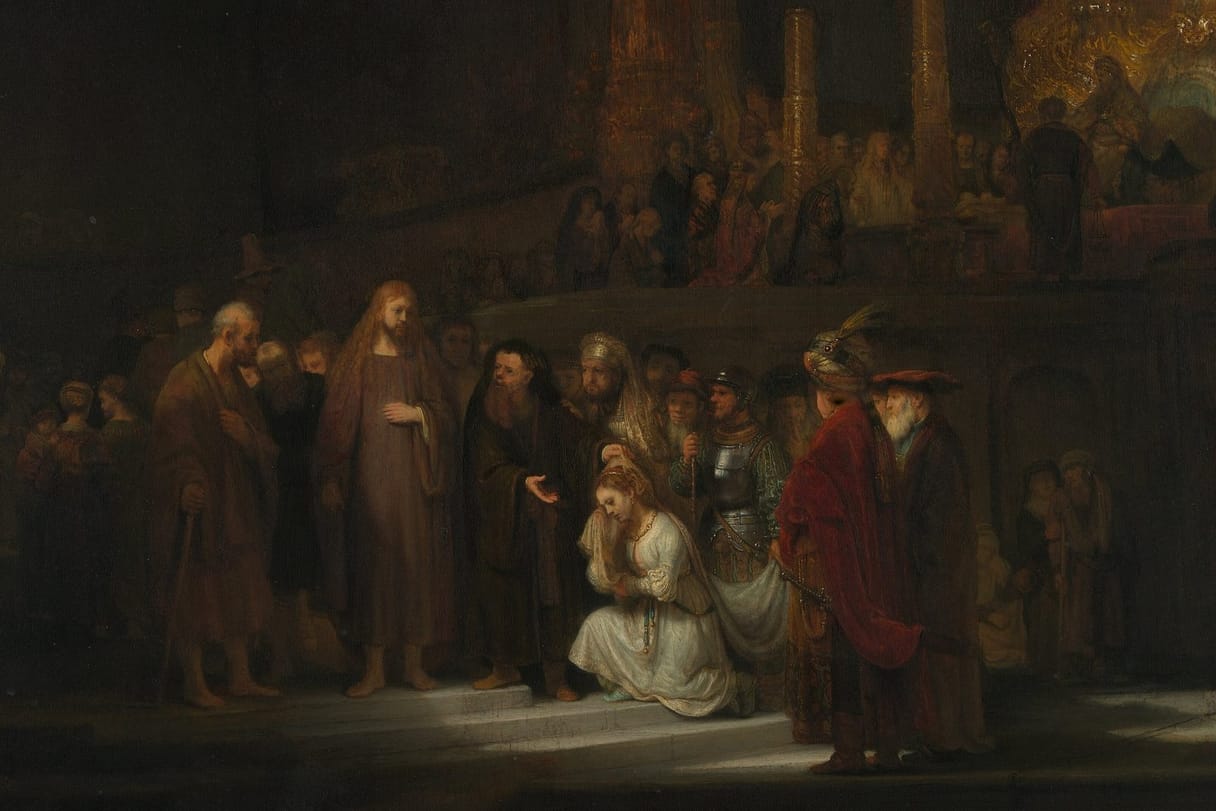 In a vast, dark temple, a woman in white kneels in a pool of light before Jesus as her accusers crowd around.