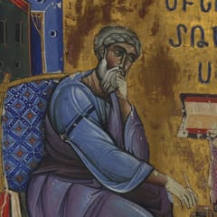 A gray-bearded evangelist in a blue robe sits in a cushioned chair with his hand at his chin in thought, before a lectern holding an open book, under his name in Armenian letters on a gold ground.