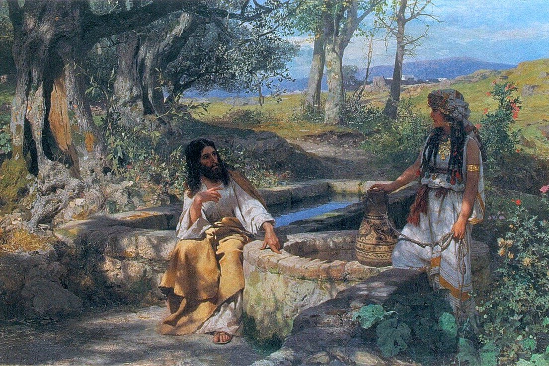 Jesus sits by a stone well in the shade of olive trees, talking with a woman who stands holding a water jar in the bright sun.