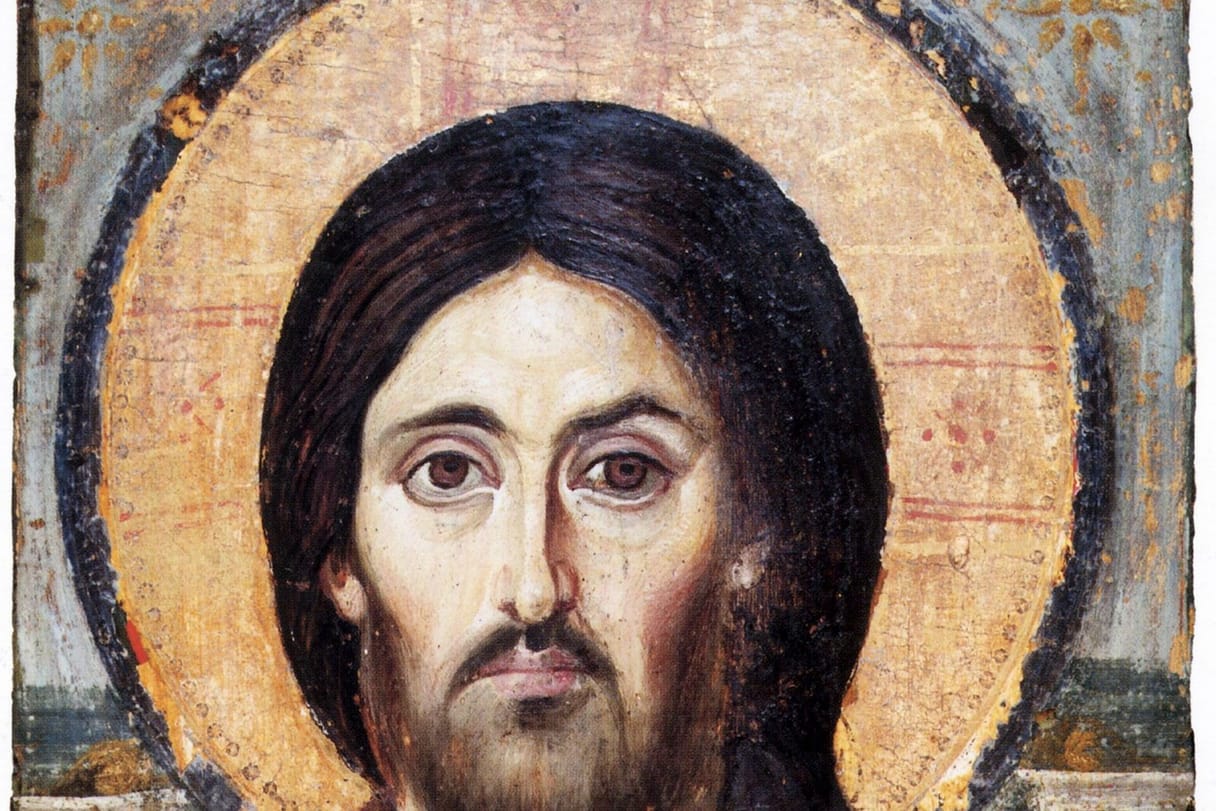 An ancient icon shows the face of Christ with long dark hair and a beard, framed by a gold halo.