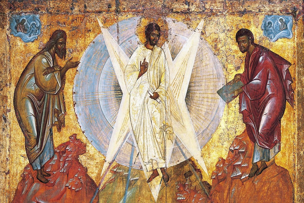 Christ in shining white robes stands on a mountain peak inside a pale blue circle of light crossed by white rays, with Elijah on a rock to his left and Moses, holding a tablet, on a rock to his right, against a gold background.