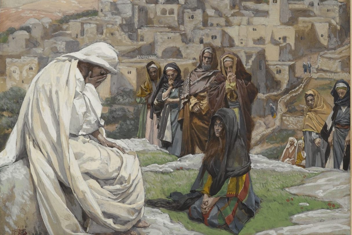 Jesus, wrapped in a white cloak, sits on a rock and covers his eyes with his hand, while a woman in a dark shawl kneels before him and mourners watch outside a hillside town.